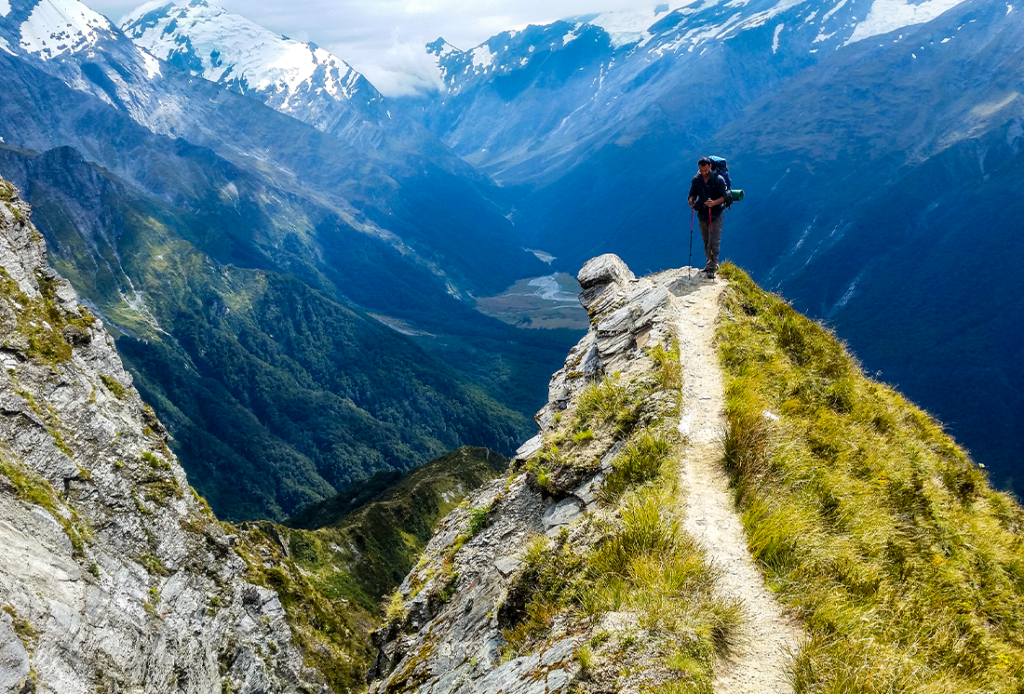 Traveler at the edge of a cliff with amazing view behind him.Cascade Saddle, Mount Aspiring National Park, New Zealand